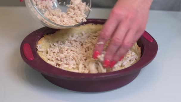 Kvinna lägger styckat kött av kyckling i en form med deg och häller slagna ägg med gräddfil — Stockvideo