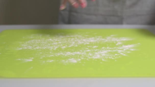 Женщина посыпает стол мукой и кладет на него тесто из пищевой пленки — стоковое видео