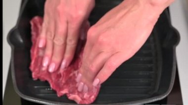 Female chef puts raw outside skirt beef steak on hot grill pan