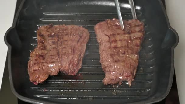 Femme chef flips frit hors jupe steaks de bœuf sur la poêle chaude avec le ferry — Video