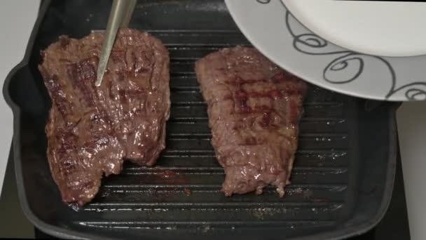 Female chef puts the tongs on the plate fried outside skirt beef steaks — Stok video