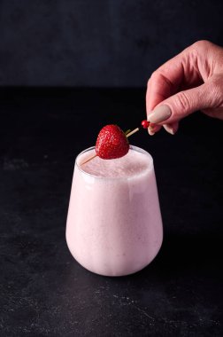 Kadın eli Lassi 'ye çilek koyar.