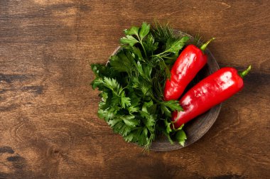 Ahşap arka planda seramik tabakta kırmızı biber ve maydanoz.