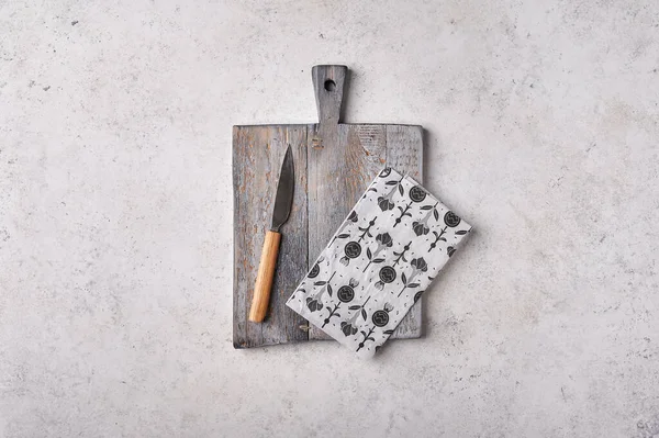Стара дерев'яна обробна дошка з ножем та ремісничим папером на сірому текстурованому фоні — стокове фото