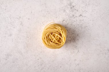 Gri desenli arka planda pişmemiş çiğ fettucine.