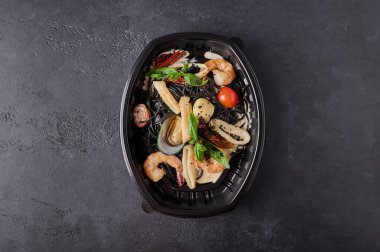 Deniz ürünleri, domates ve fesleğenli siyah spagetti.