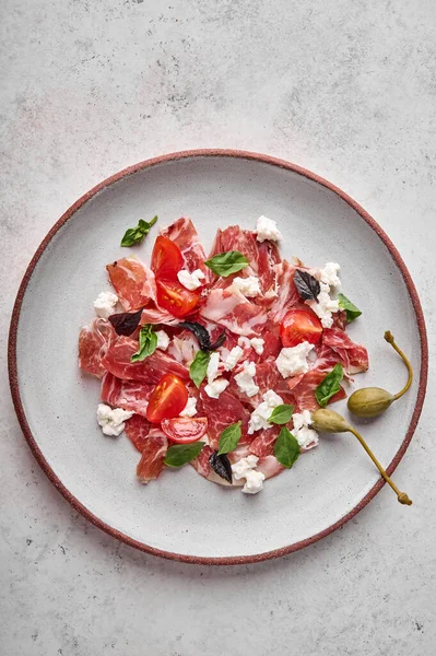 Vertical orientation prosciutto coppa di parma ham slices with ricotta cheese, tomato, capers — Stock Photo, Image