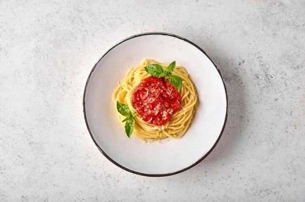 Top view spaghetti in tomato sauce, parmesan cheese and basil on white plate — Stock Photo, Image