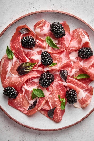 Food background slices of prosciutto coppa di parma ham with basil and blackberry — Stock Photo, Image