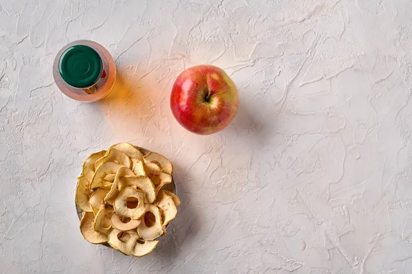 Äppelchips på tallrik, äppelfrukt och flaska med juice — Stockfoto