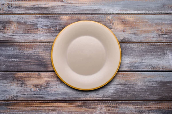 Light empty plate with brown edge on from boards wooden background, top view — Stock Photo, Image