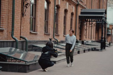Genç bayan fotoğrafçı kız arkadaşıyla sokakta geziniyor. Gezginler şehirde yürürler. Şehre bak..