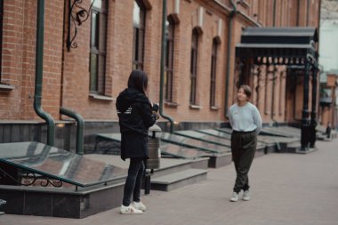 Genç bayan fotoğrafçı kız arkadaşıyla sokakta geziniyor. Gezginler şehirde yürürler. Şehre bak..