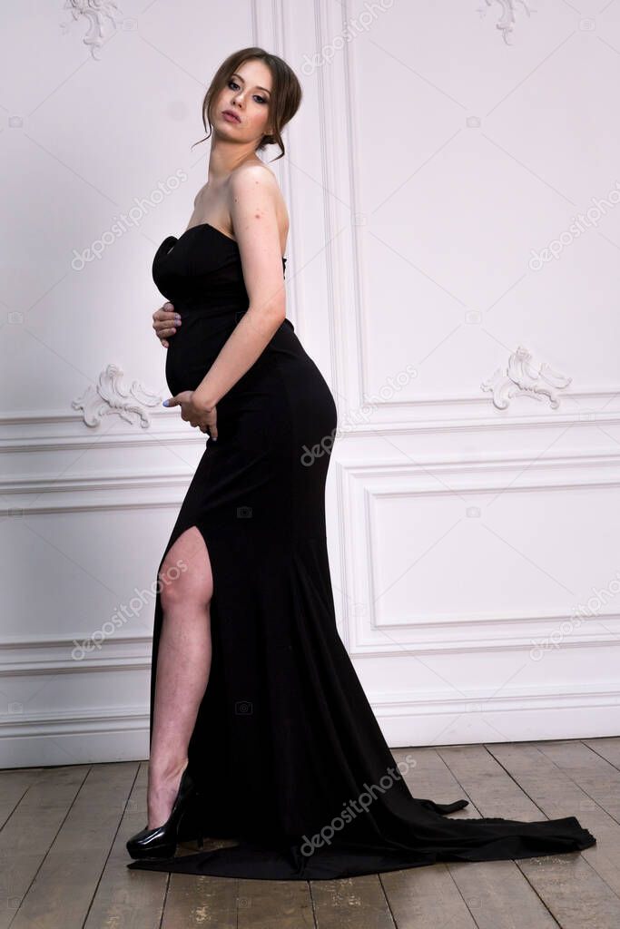 Beautiful pregnant girl on 40 week in studio. nine months pregnant girl in black dress posing on photo shoot. stylish pregnant woman. mother to be.Young pretty pregnant woman in black dress in studio