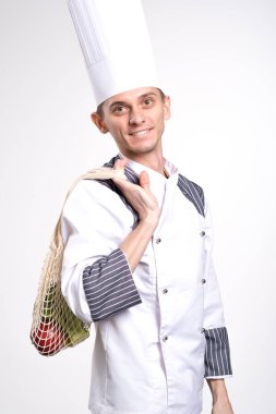 Teslimat konsepti. Şef ürünleri getiriyor. Taze sebzeler ve meyveler beyaz arka planda eko iplik torbasında. Sağlıklı bir yaşam tarzı. Sıfır atık.