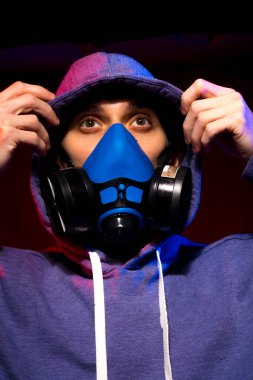 Bilinmeyen bir adamın portresi, karanlık arka planda neon maske takan bir hacker. Neon ışıklandırması yakınında silah tutan çift ırklı siber punk oyuncusunun seçici odak noktası