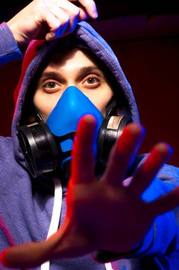 Bilinmeyen bir adamın portresi, karanlık arka planda neon maske takan bir hacker. Neon ışıklandırması yakınında silah tutan çift ırklı siber punk oyuncusunun seçici odak noktası
