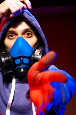 Bilinmeyen bir adamın portresi, karanlık arka planda neon maske takan bir hacker. Neon ışıklandırması yakınında silah tutan çift ırklı siber punk oyuncusunun seçici odak noktası