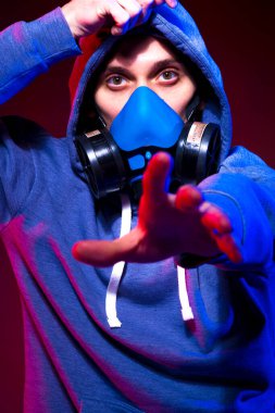 Bilinmeyen bir adamın portresi, karanlık arka planda neon maske takan bir hacker. Neon ışıklandırması yakınında silah tutan çift ırklı siber punk oyuncusunun seçici odak noktası