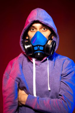 Bilinmeyen bir adamın portresi, karanlık arka planda neon maske takan bir hacker. Neon ışıklandırması yakınında silah tutan çift ırklı siber punk oyuncusunun seçici odak noktası