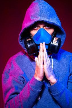 Bilinmeyen bir adamın portresi, karanlık arka planda neon maske takan bir hacker. Neon ışıklandırması yakınında silah tutan çift ırklı siber punk oyuncusunun seçici odak noktası