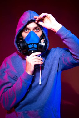 Bilinmeyen bir adamın portresi, karanlık arka planda neon maske takan bir hacker. Neon ışıklandırması yakınında silah tutan çift ırklı siber punk oyuncusunun seçici odak noktası
