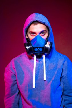 Bilinmeyen bir adamın portresi, karanlık arka planda neon maske takan bir hacker. Neon ışıklandırması yakınında silah tutan çift ırklı siber punk oyuncusunun seçici odak noktası