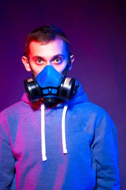 Bilinmeyen bir adamın portresi, karanlık arka planda neon maske takan bir hacker. Neon ışıklandırması yakınında silah tutan çift ırklı siber punk oyuncusunun seçici odak noktası