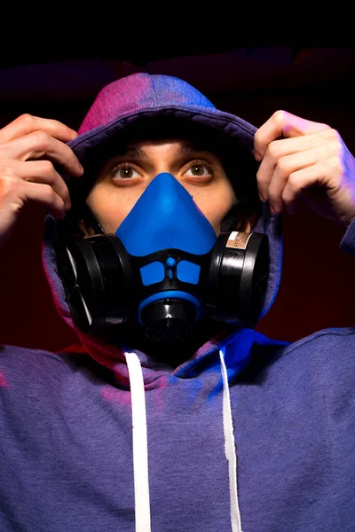 Bilinmeyen bir adamın portresi, karanlık arka planda neon maske takan bir hacker. Neon ışıklandırması yakınında silah tutan çift ırklı siber punk oyuncusunun seçici odak noktası