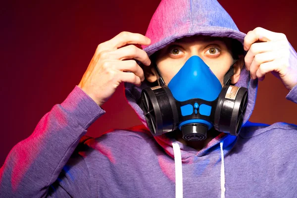 Bilinmeyen bir adamın portresi, karanlık arka planda neon maske takan bir hacker. Neon ışıklandırması yakınında silah tutan çift ırklı siber punk oyuncusunun seçici odak noktası