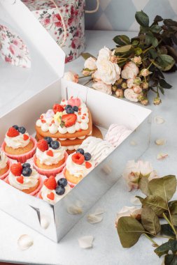 Bakım paketi, içinde pelerinli kek ve güller olan mevsimlik hediye kutusu. Tatiller için kişisel çevre dostu sepet. Sevgililer Günü kavramı. Üst manzara, düz uzanma
