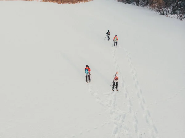 Aerial. Snowshoe walker. Outdoor winter activity and healthy lifestyle. Winter sport activity. Woman hiker hiking with backpack and snowshoes snowshoeing on snow trail forest at sunset