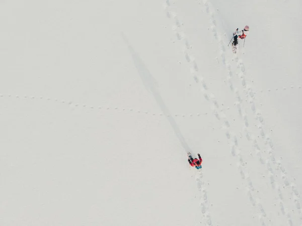 Aerial. Snowshoe walker. Outdoor winter activity and healthy lifestyle. Winter sport activity. Woman hiker hiking with backpack and snowshoes snowshoeing on snow trail forest at sunset