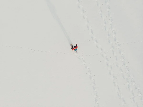 Aerial. Snowshoe walker. Outdoor winter activity and healthy lifestyle. Winter sport activity. Woman hiker hiking with backpack and snowshoes snowshoeing on snow trail forest at sunset