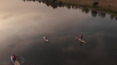 Göldeki SUP tahtalı turistlerin en iyi görüntüsü. Sörf yapan insanlarla dolu güzel, berrak bir su. Arka planda kürek çeken insanların olduğu deniz manzarası