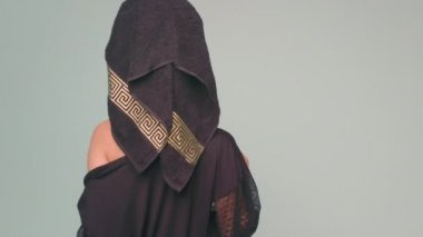 Kafasında havlu olan siyah ipek bornozlu genç bir kadın. İç çamaşırsız kız yavaşça bornozunu çıkarıyor.