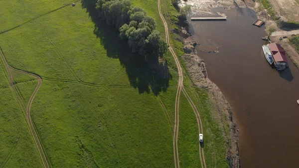 緑の草や牧草地の背景にある道 白い車に乗る — ストック写真