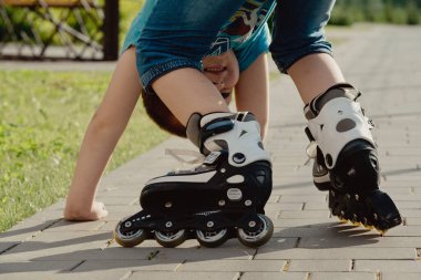 Bir çocuk patenlerle düştükten sonra yerden kalkmaya çalışıyor. Bisiklet süren ya da yuvarlanan bir çocuk düştü ve bacağını yaraladı.