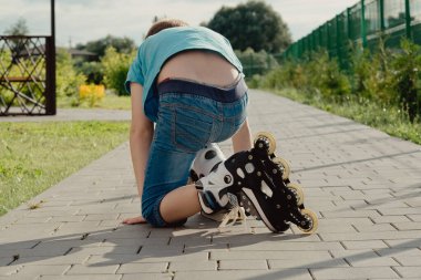 Bir çocuk patenlerle düştükten sonra yerden kalkmaya çalışıyor. Bisiklet süren ya da yuvarlanan bir çocuk düştü ve bacağını yaraladı.