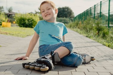 Bir çocuk patenlerle düştükten sonra yerden kalkmaya çalışıyor. Bisiklet süren ya da yuvarlanan bir çocuk düştü ve bacağını yaraladı.
