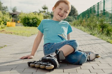Bir çocuk patenlerle düştükten sonra yerden kalkmaya çalışıyor. Bisiklet süren ya da yuvarlanan bir çocuk düştü ve bacağını yaraladı.