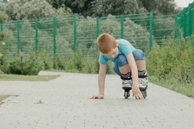 Bir çocuk patenlerle düştükten sonra yerden kalkmaya çalışıyor. Bisiklet süren ya da yuvarlanan bir çocuk düştü ve bacağını yaraladı.