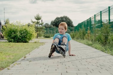 Bir çocuk patenlerle düştükten sonra yerden kalkmaya çalışıyor. Bisiklet süren ya da yuvarlanan bir çocuk düştü ve bacağını yaraladı.