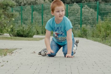 Bir çocuk patenlerle düştükten sonra yerden kalkmaya çalışıyor. Bisiklet süren ya da yuvarlanan bir çocuk düştü ve bacağını yaraladı.