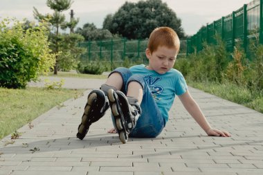 Bir çocuk patenlerle düştükten sonra yerden kalkmaya çalışıyor. Bisiklet süren ya da yuvarlanan bir çocuk düştü ve bacağını yaraladı.