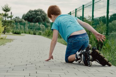 Bir çocuk patenlerle düştükten sonra yerden kalkmaya çalışıyor. Bisiklet süren ya da yuvarlanan bir çocuk düştü ve bacağını yaraladı.
