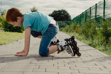 Bir çocuk patenlerle düştükten sonra yerden kalkmaya çalışıyor. Bisiklet süren ya da yuvarlanan bir çocuk düştü ve bacağını yaraladı.