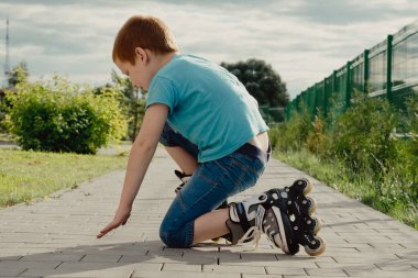 Bir çocuk patenlerle düştükten sonra yerden kalkmaya çalışıyor. Bisiklet süren ya da yuvarlanan bir çocuk düştü ve bacağını yaraladı.
