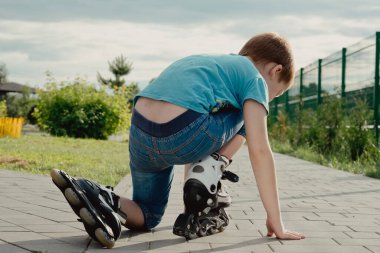 Bir çocuk patenlerle düştükten sonra yerden kalkmaya çalışıyor. Bisiklet süren ya da yuvarlanan bir çocuk düştü ve bacağını yaraladı.