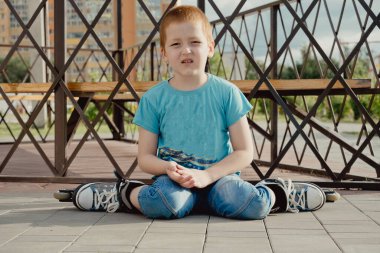 Bir çocuk patenlerle düştükten sonra yerden kalkmaya çalışıyor. Bisiklet süren ya da yuvarlanan bir çocuk düştü ve bacağını yaraladı.